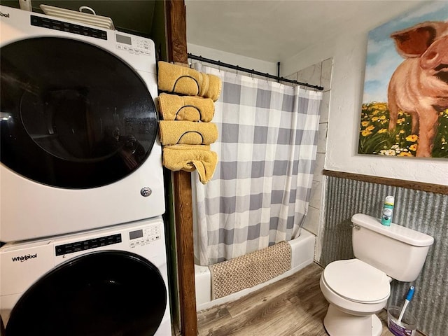 bathroom featuring wood-type flooring, stacked washer and clothes dryer, shower / bath combination with curtain, and toilet