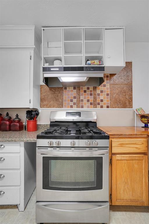 kitchen with tasteful backsplash, white cabinetry, and stainless steel range with gas cooktop