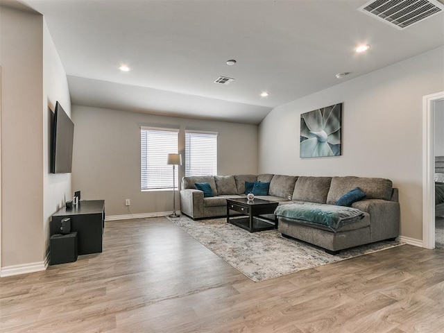 living room featuring lofted ceiling and light hardwood / wood-style floors