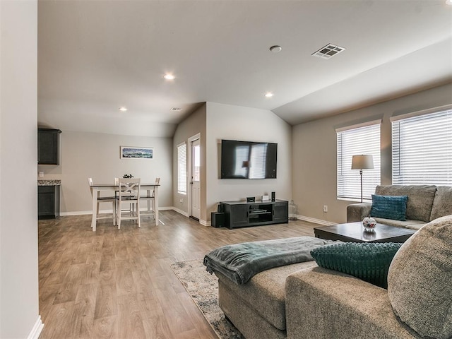 living room featuring light hardwood / wood-style flooring, a wealth of natural light, and vaulted ceiling