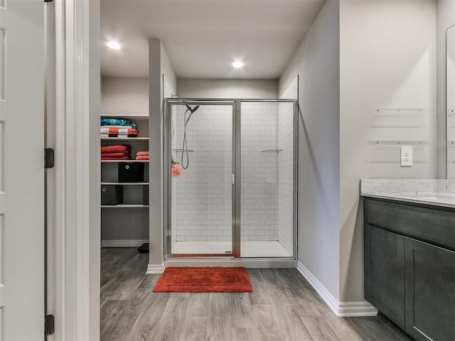 bathroom featuring hardwood / wood-style flooring, vanity, and a shower with door