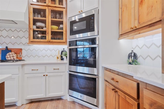 kitchen featuring built in microwave, double oven, white cabinetry, and white gas stovetop