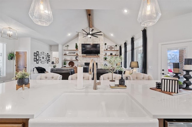 kitchen with hanging light fixtures, a fireplace, lofted ceiling with beams, and sink