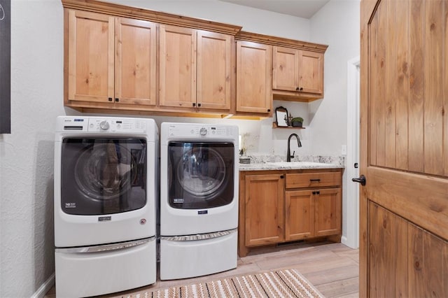 washroom with cabinets, washing machine and clothes dryer, light hardwood / wood-style floors, and sink