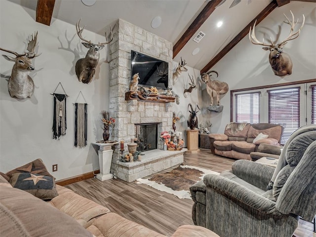 living room with beamed ceiling, a stone fireplace, high vaulted ceiling, and light hardwood / wood-style flooring