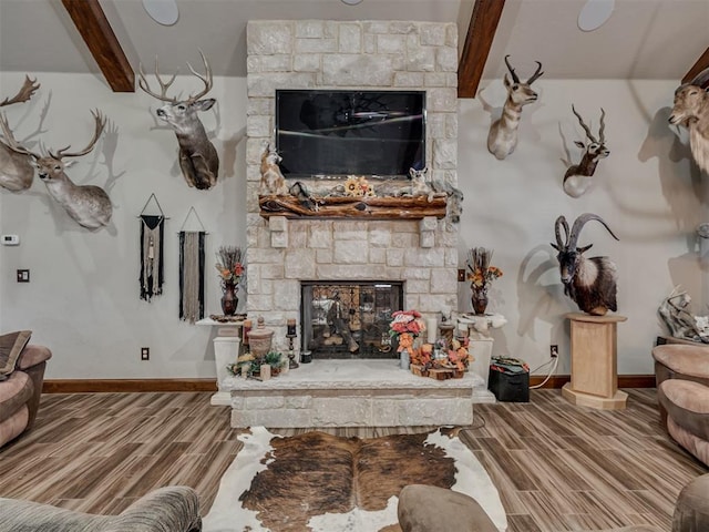 living room with beam ceiling and a stone fireplace