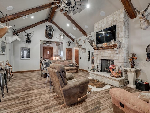 living room featuring beamed ceiling, a stone fireplace, and high vaulted ceiling