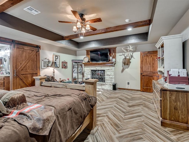 bedroom with light parquet flooring, a barn door, a stone fireplace, and beam ceiling