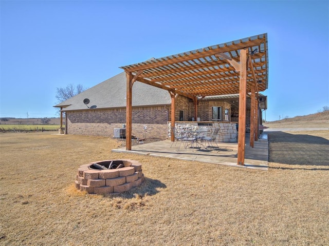 view of yard featuring a patio, a pergola, central AC unit, and a fire pit