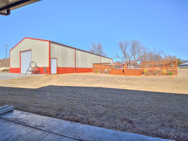 view of yard featuring a garage, an outbuilding, and a deck