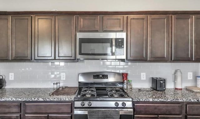 kitchen featuring stone counters, appliances with stainless steel finishes, and dark brown cabinetry