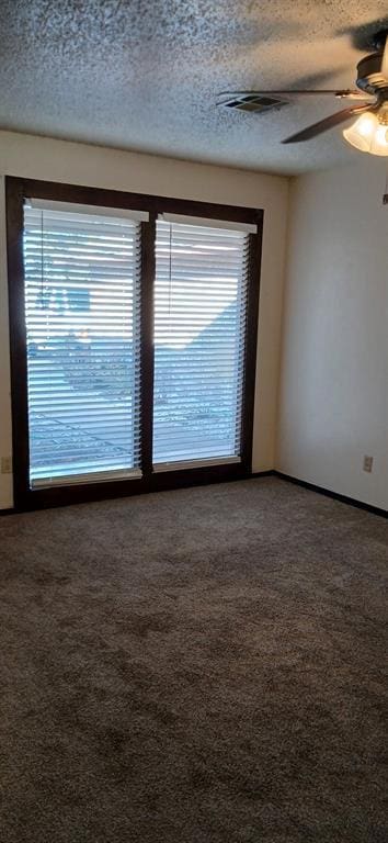 carpeted spare room featuring ceiling fan and a textured ceiling