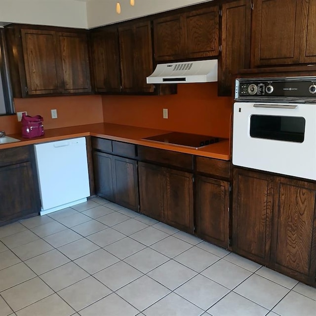 kitchen with light tile patterned flooring, white appliances, and dark brown cabinets