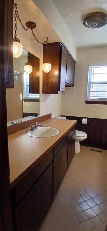 bathroom featuring tile patterned flooring, vanity, a textured ceiling, and toilet