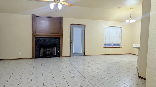 unfurnished living room featuring a premium fireplace, ceiling fan with notable chandelier, and light tile patterned floors