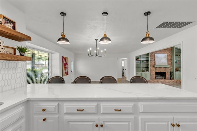 kitchen with light stone counters, built in shelves, kitchen peninsula, and white cabinets