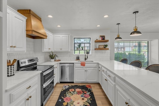 kitchen featuring white cabinetry, sink, custom exhaust hood, and appliances with stainless steel finishes