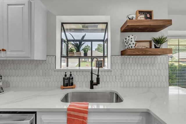 kitchen featuring sink, white cabinetry, tasteful backsplash, plenty of natural light, and light stone countertops