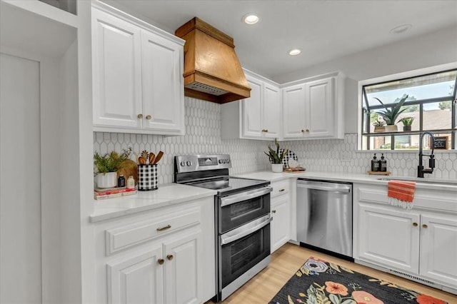 kitchen with sink, white cabinetry, tasteful backsplash, custom range hood, and stainless steel appliances