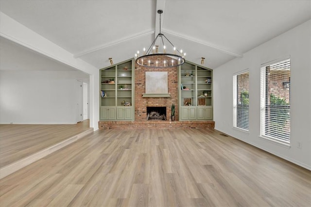 unfurnished living room featuring a brick fireplace, vaulted ceiling with beams, an inviting chandelier, and built in shelves