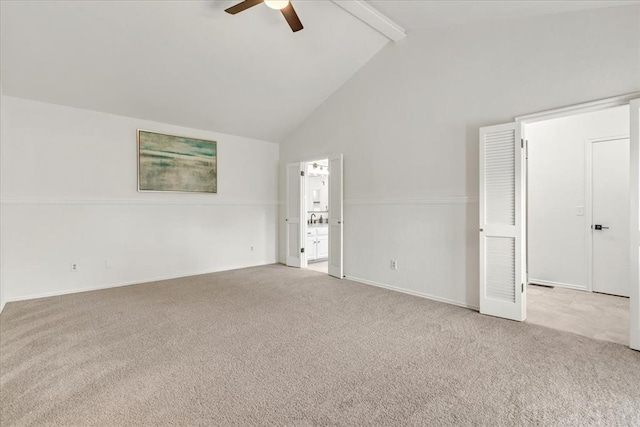 carpeted empty room with beam ceiling, high vaulted ceiling, and ceiling fan