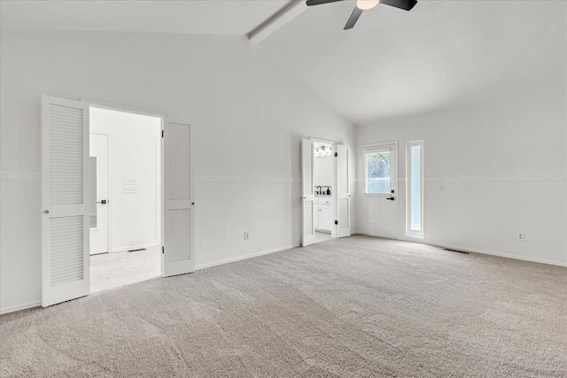 carpeted empty room with ceiling fan, high vaulted ceiling, and beam ceiling