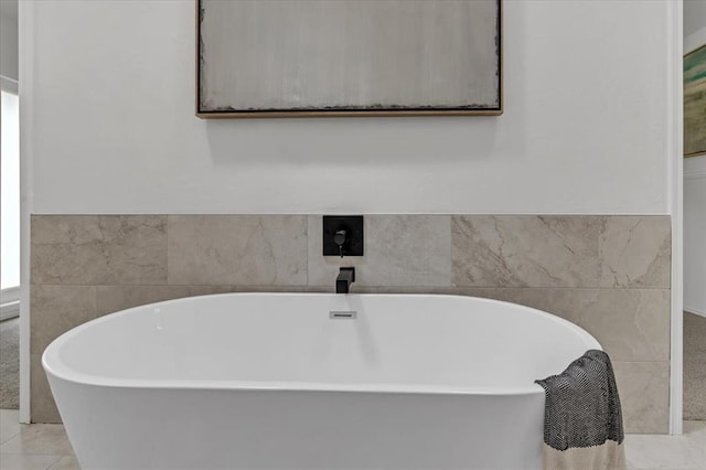 bathroom featuring tile patterned flooring, a bath, and tile walls