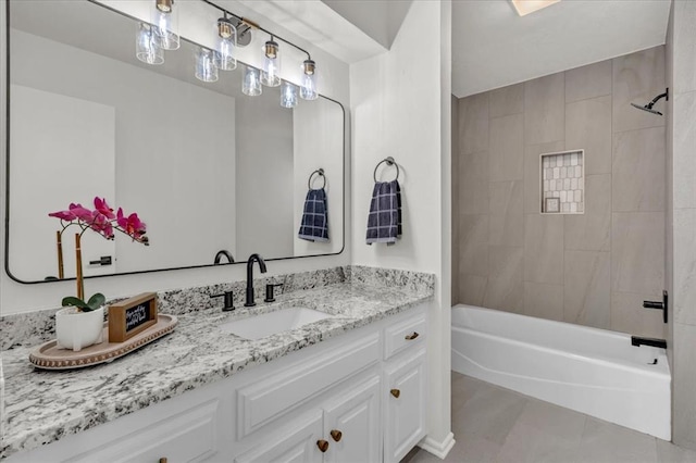 bathroom featuring tile patterned flooring, tiled shower / bath, and vanity