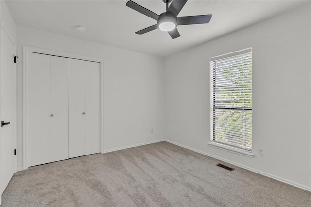 unfurnished bedroom with light carpet, ceiling fan, and a closet