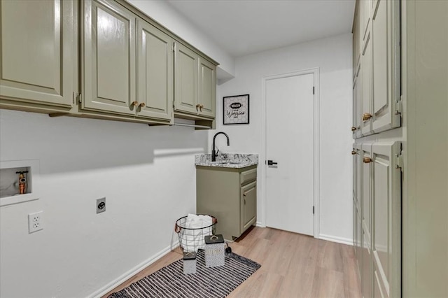 washroom featuring sink, cabinets, washer hookup, hookup for an electric dryer, and light hardwood / wood-style flooring