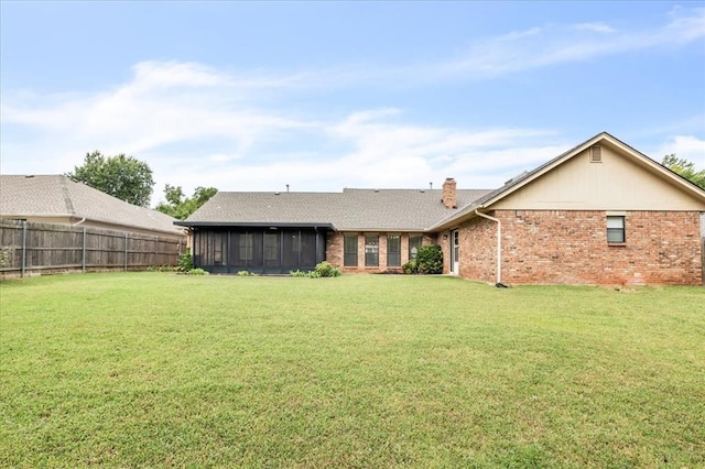 rear view of house with a sunroom and a lawn