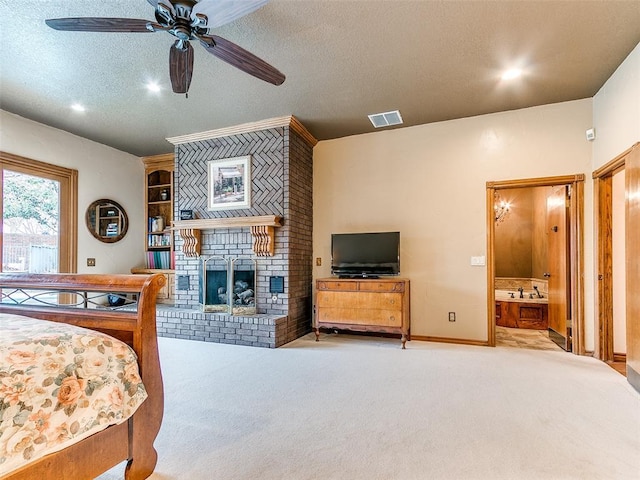 bedroom with ensuite bath, a textured ceiling, ceiling fan, a fireplace, and light carpet