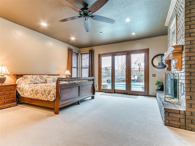 carpeted bedroom with ceiling fan, access to outside, a brick fireplace, and a textured ceiling