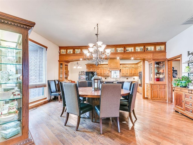 dining room featuring light wood-type flooring and an inviting chandelier