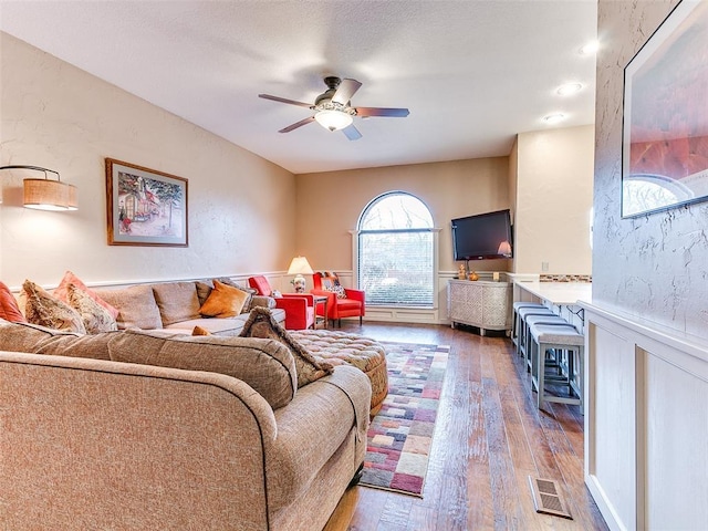 living room featuring ceiling fan and dark wood-type flooring