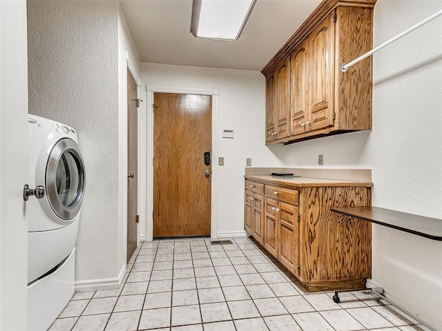 laundry room featuring light tile patterned floors, cabinets, and washer / dryer