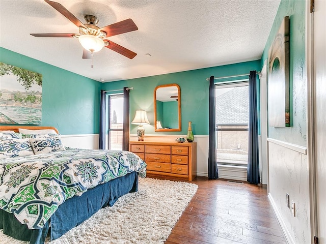 bedroom featuring ceiling fan, dark wood-type flooring, and a textured ceiling