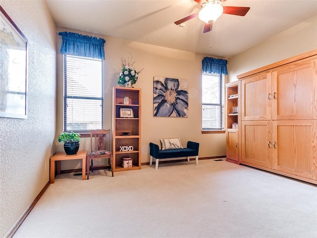 living area featuring light carpet and ceiling fan