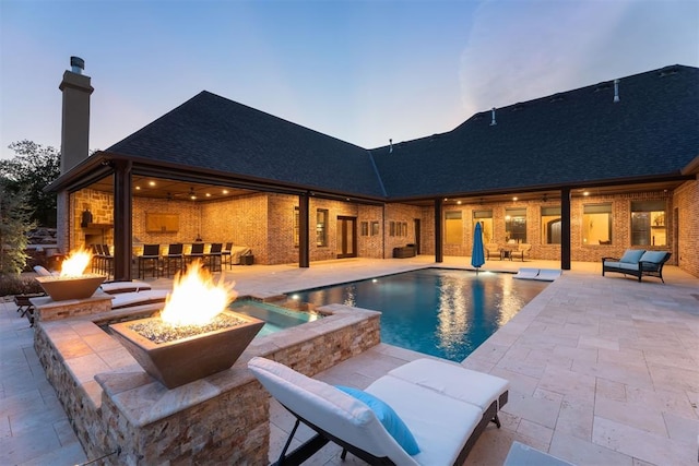 pool at dusk featuring a patio and a fire pit