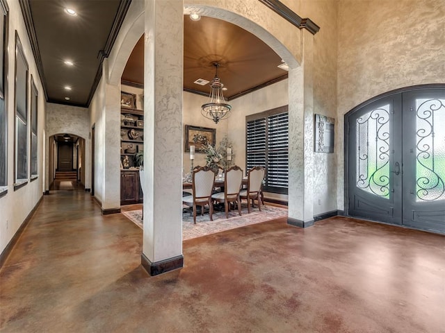 entryway featuring french doors, crown molding, an inviting chandelier, and a high ceiling