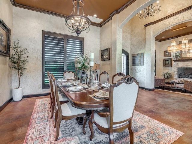 dining room with a high ceiling, ornamental molding, a notable chandelier, and a fireplace