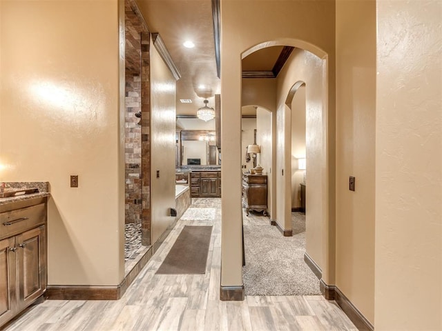 corridor featuring ornamental molding and light hardwood / wood-style floors