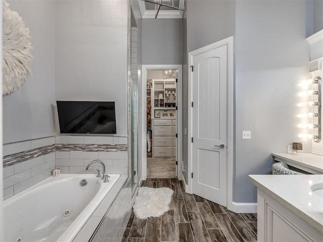 bathroom featuring vanity, ornamental molding, and tiled bath