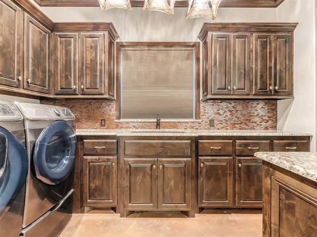 clothes washing area with separate washer and dryer, sink, and cabinets