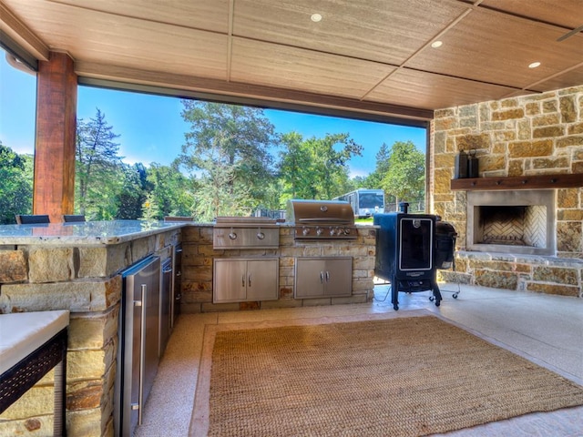 view of patio / terrace featuring grilling area, an outdoor stone fireplace, and exterior kitchen