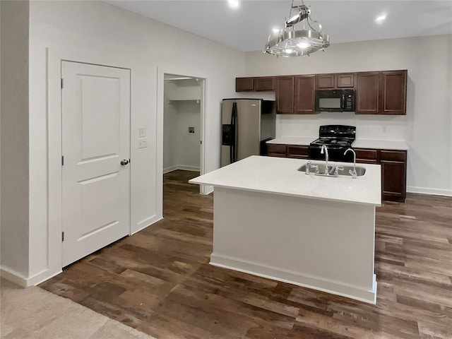 kitchen featuring dark hardwood / wood-style floors, pendant lighting, dark brown cabinetry, black appliances, and a center island with sink