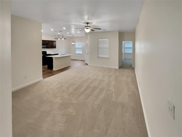 unfurnished living room with sink, light carpet, and ceiling fan