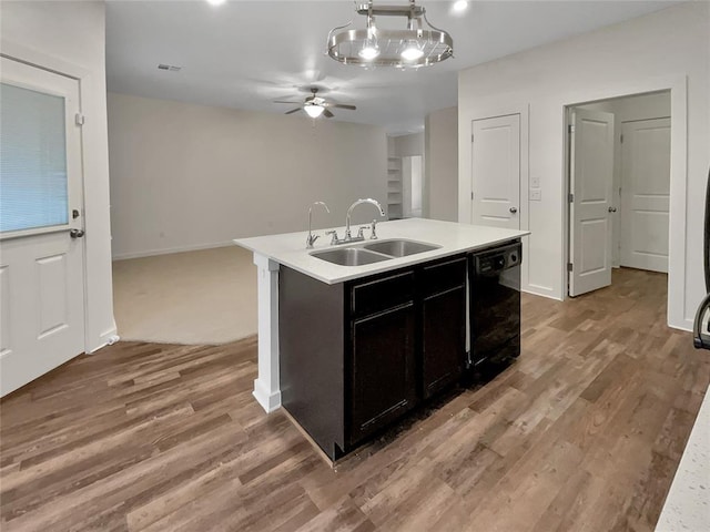 kitchen with sink, dishwasher, light hardwood / wood-style floors, an island with sink, and decorative light fixtures