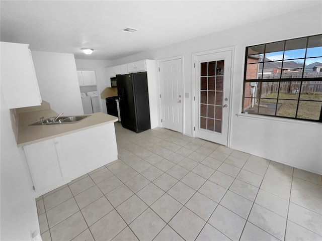 kitchen featuring white cabinets, washer and clothes dryer, sink, and black appliances