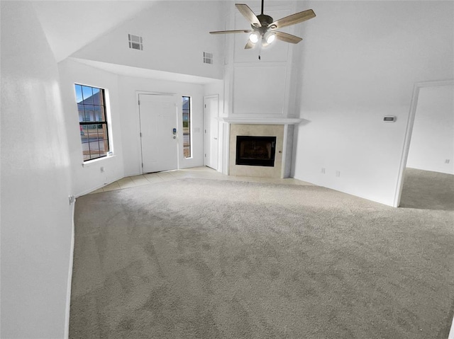 unfurnished living room with ceiling fan, light colored carpet, a large fireplace, and high vaulted ceiling